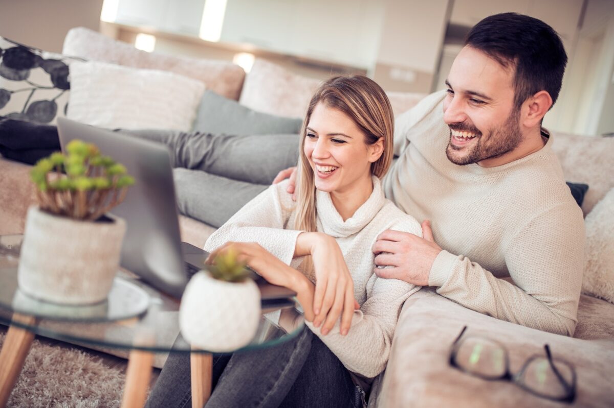 Couple smiling and enjoying a relaxing time in their recently cleaned living room.